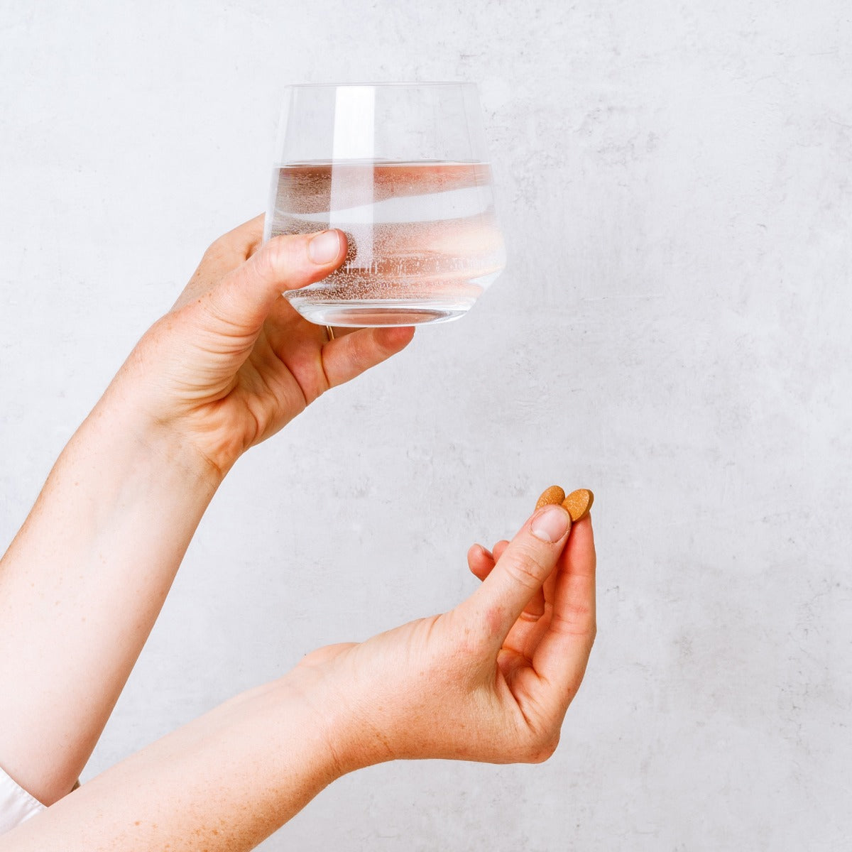 Blood Cleanse™ tablets in hand with water glass