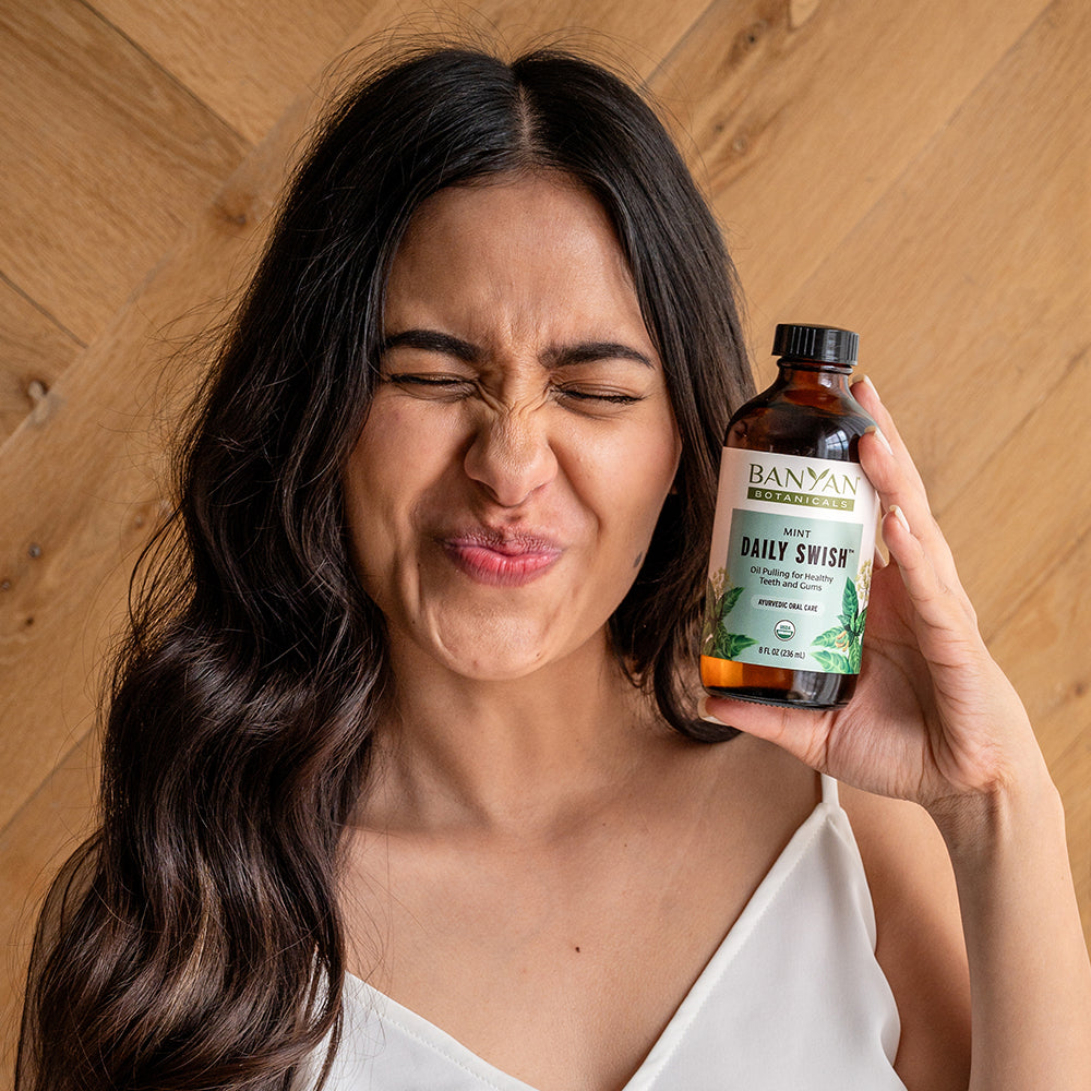 8 fl oz: Woman using Daily Swish Mint Oil Pulling 