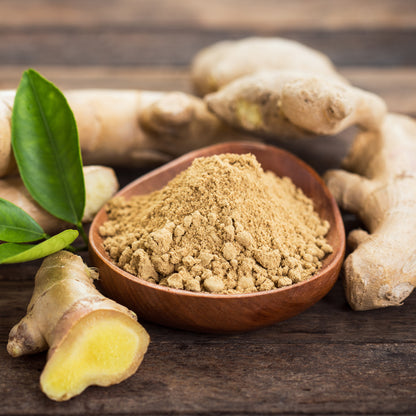 Bowl of ginger powder next to ginger roots